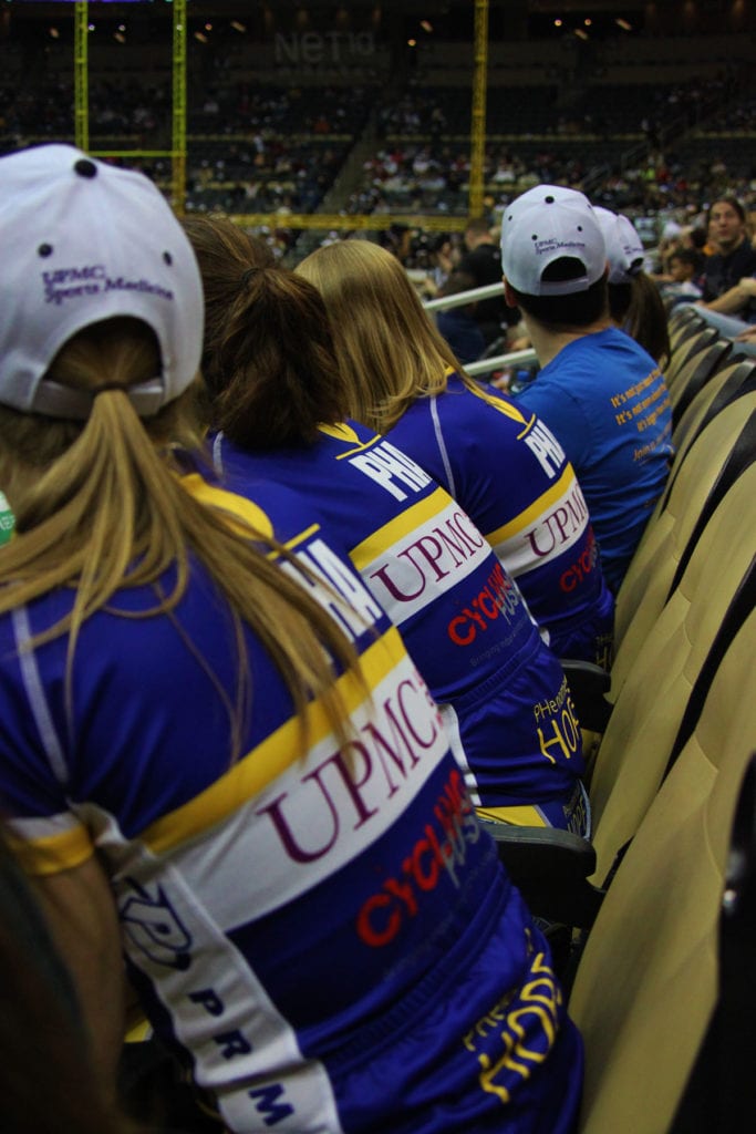 Members of Team PHenomenal Hope watching an indoor event, wearing their kit jerseys