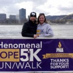 Race organizer Julia Feitner and her husband behind a Phenomenal Hope 5k race banner