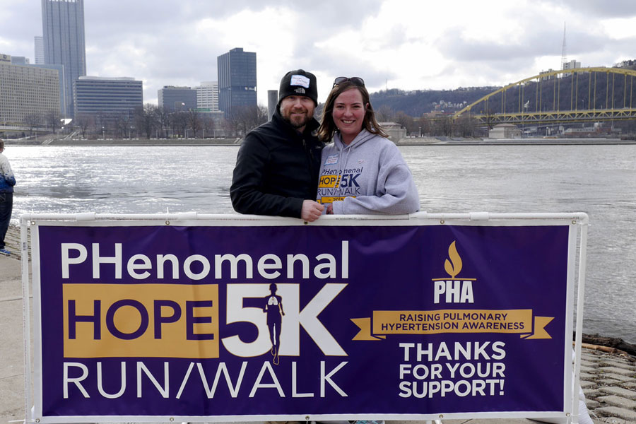 Race organizer Julia Feitner and her husband behind a Phenomenal Hope 5k race banner