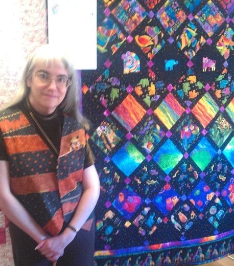 Diane Kowalik standing in front of a beautiful quilt