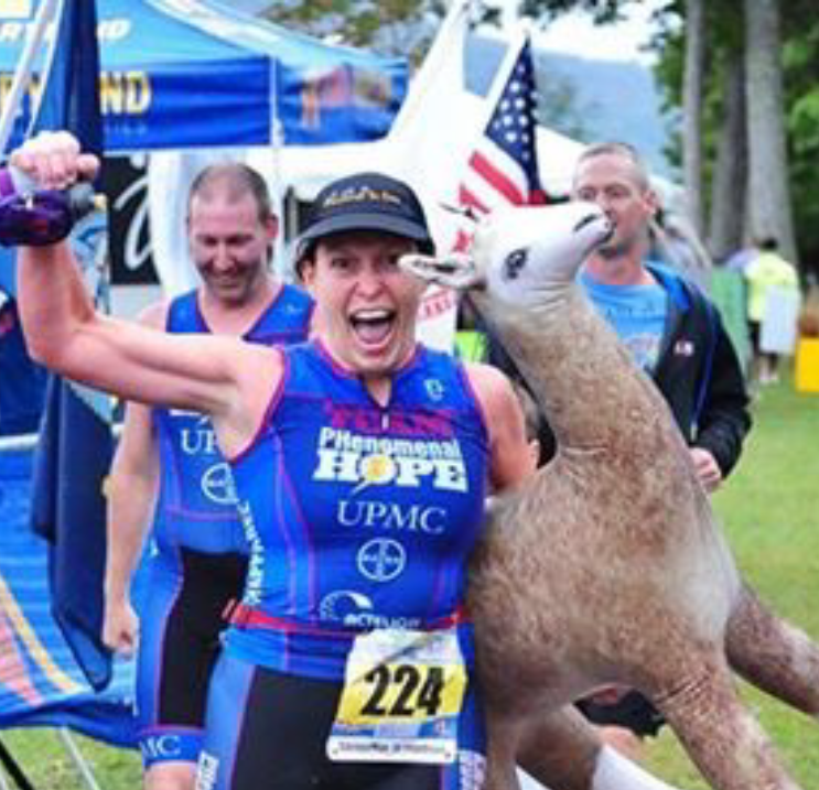 Vicki smiles as she crosses the finish line at Savageman with her Alpaca stuffed animal in tow
